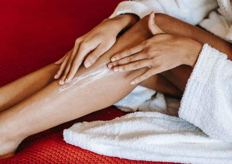 Femme étalant de la crème de chanvre sur ses jambes