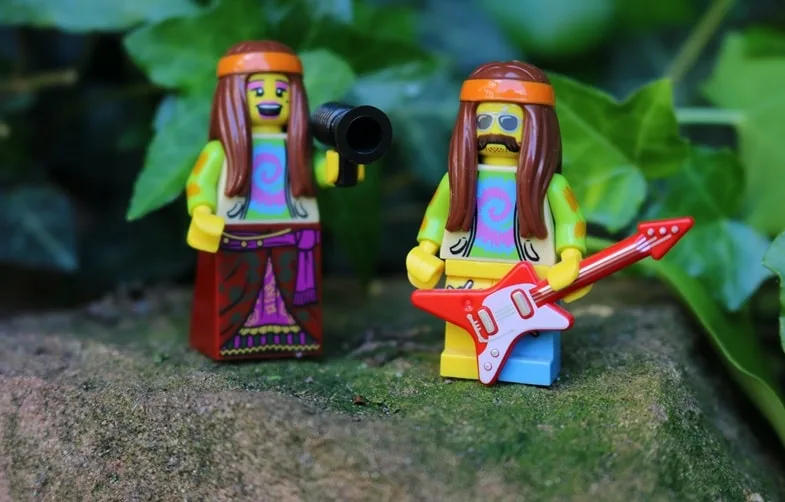 Mise en scène ludique de figurines hippies aux cheveux longs avec guitare électrique rouge et micro évoquant l'imagerie populaire des années 1970