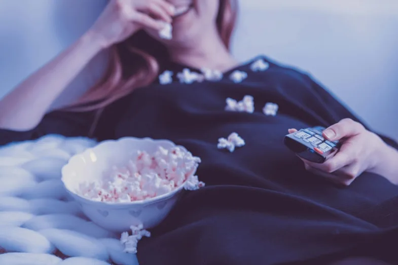 Femme regardant un film avec un bol de pop-corn illustrant l'expérience cinéphile autour des films liés à la culture cannabique