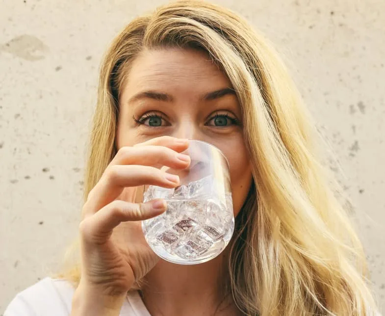 Femme buvant de l'eau au réveil illustrant le contexte d'hydratation associé aux sensations de bouche sèche documentées par l'OFDT