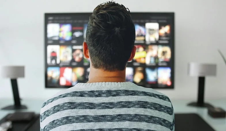 Homme devant un écran de télévision symbolisant la diffusion de films sur le cannabis et la culture cinématographique associée